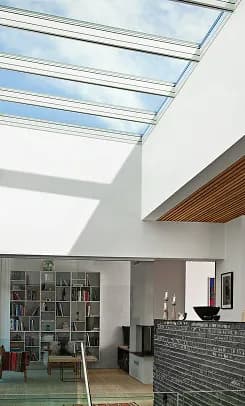 A continuous run of modular skylights along a ceiling, daylighting an open living space below.