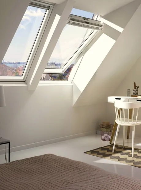 VELUX center-pivot roof windows in a sloped-ceiling room with a desk beneath.