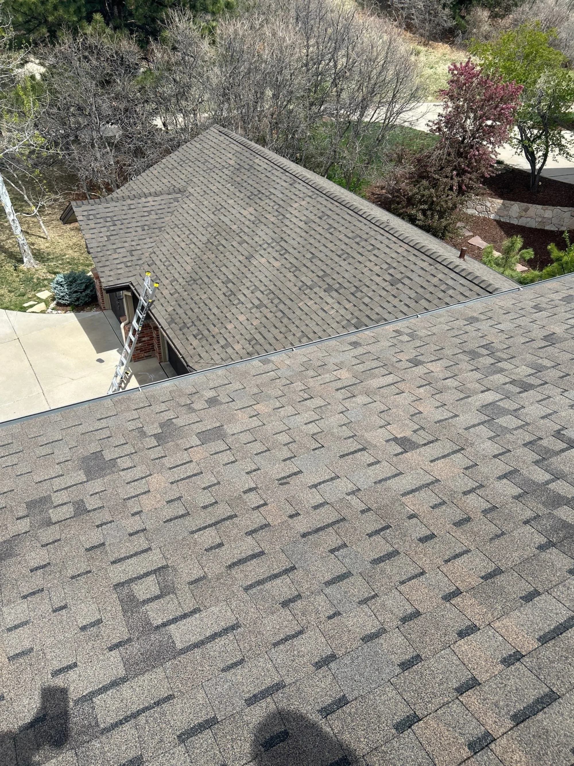 Completed roof replacement on a Castle Pines home, showing ridge and hip detail across the main and garage roofs.