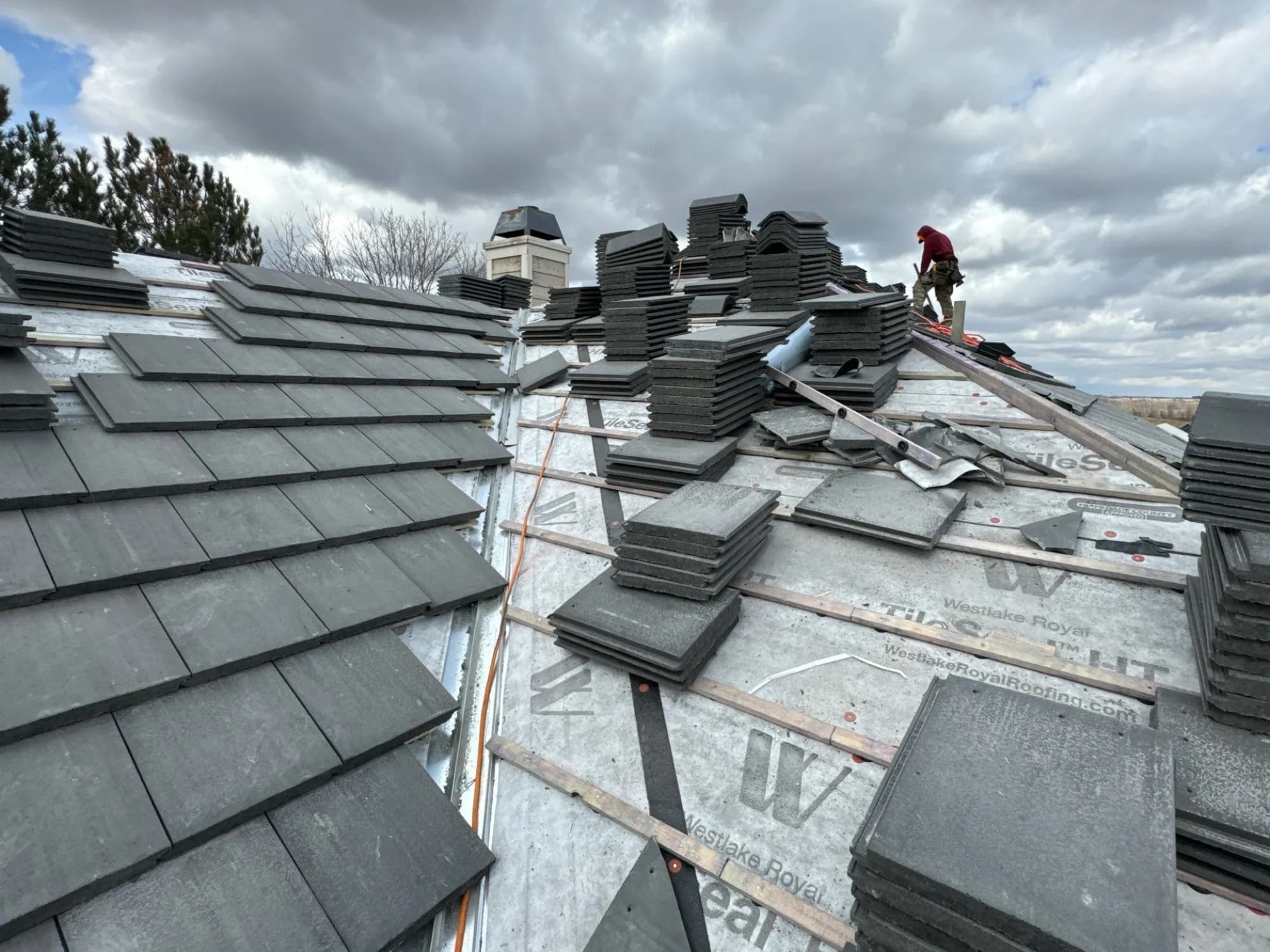 New concrete tile going down over battens and tile underlayment on a Centennial roof.