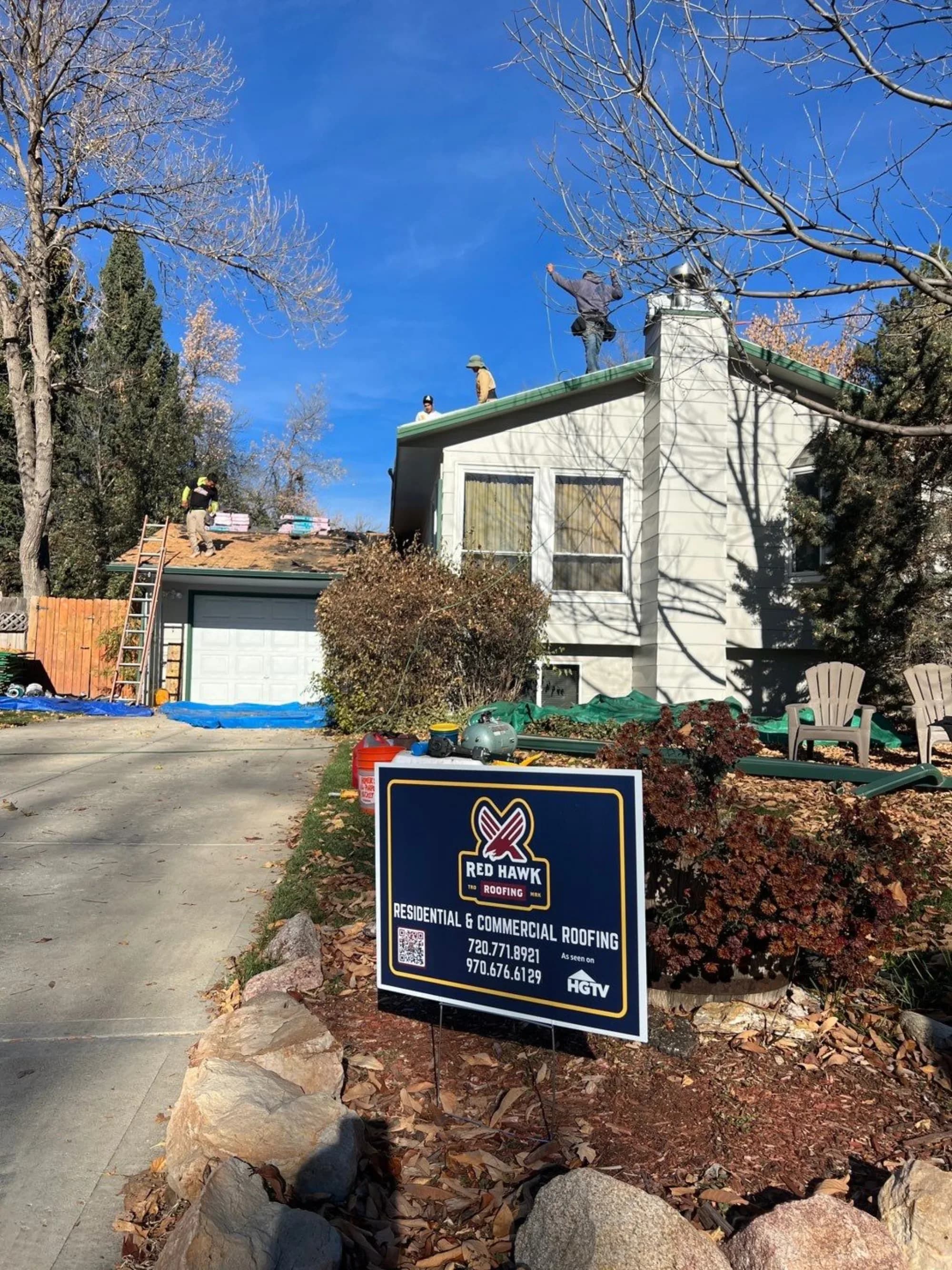 Red Hawk Roofing crew at work on a Fort Collins roof, with a Red Hawk yard sign in the foreground