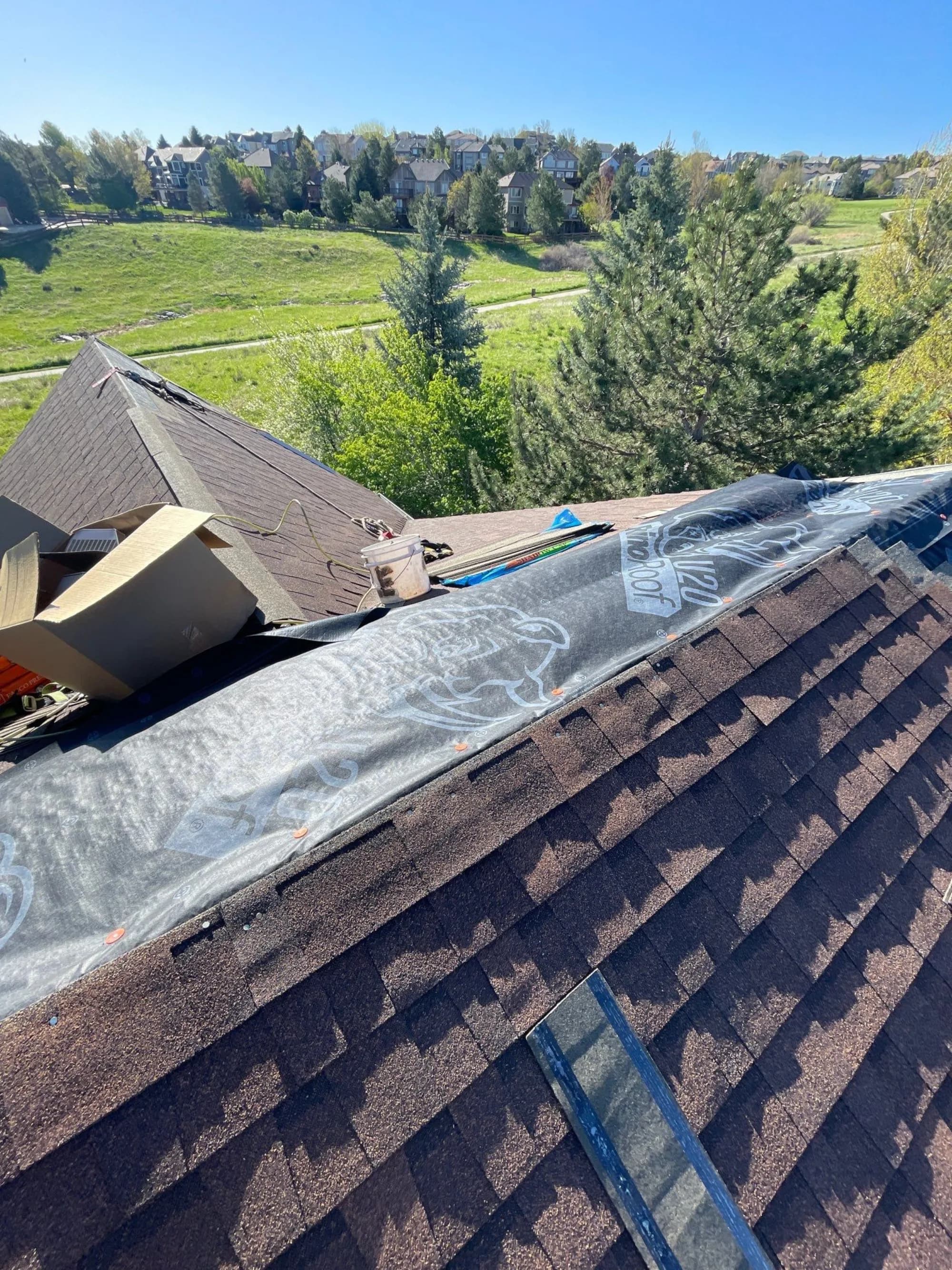 Ridge detail during a Highlands Ranch roof replacement, with ridge cap staged along the peak.