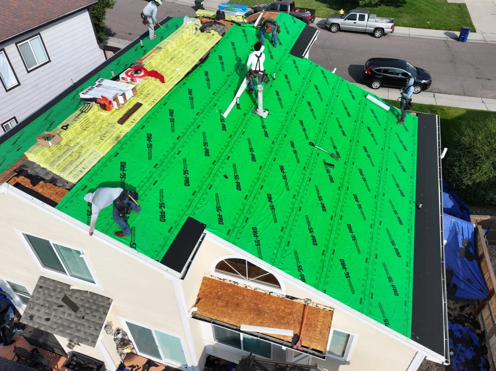 Synthetic underlayment down and crew working a Highlands Ranch roof replacement.