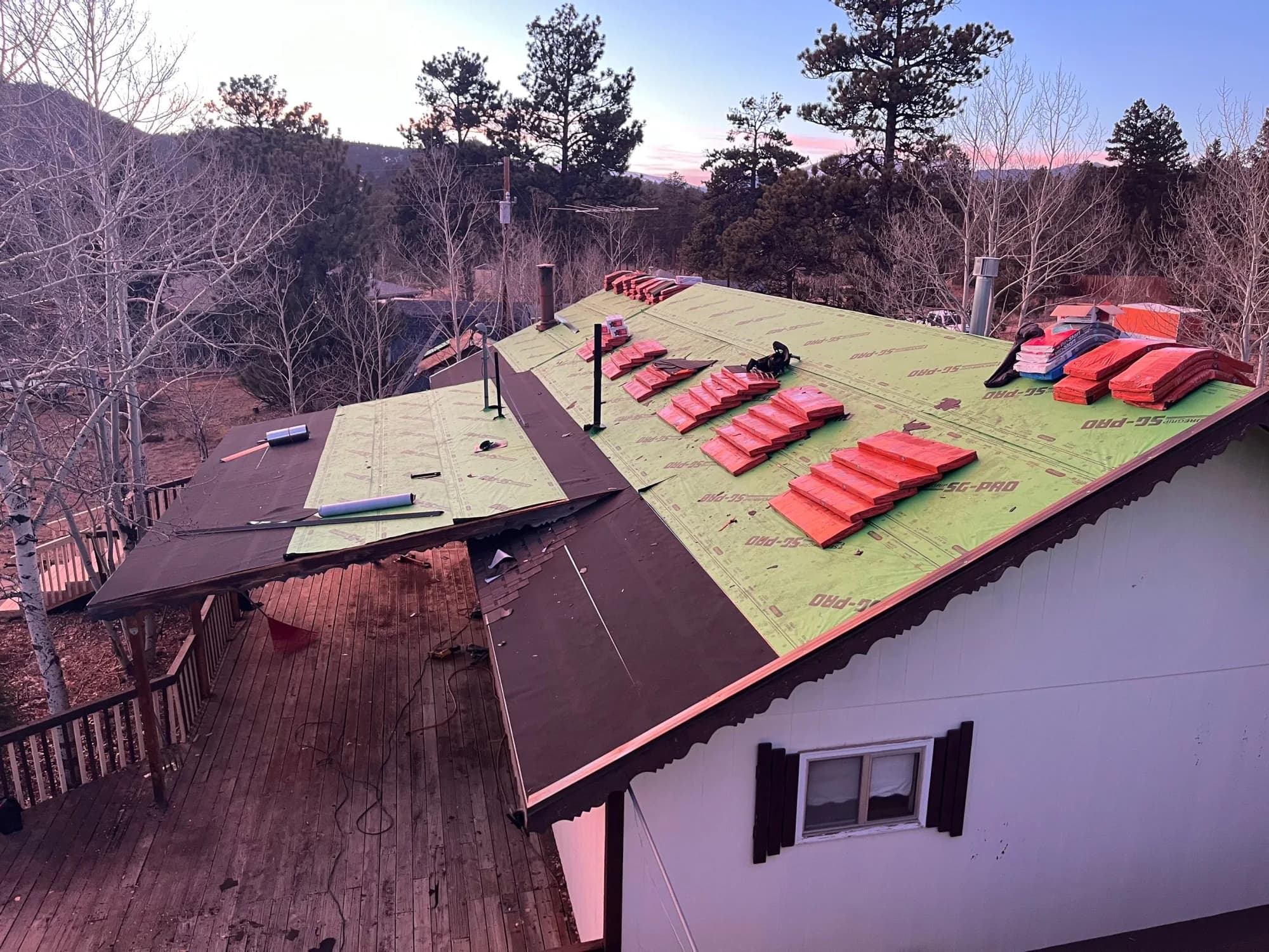 Roof replacement in progress at dusk on a Pine, Colorado mountain home.